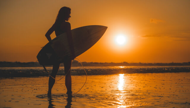 fille posant avec une planche au coucher du soleil