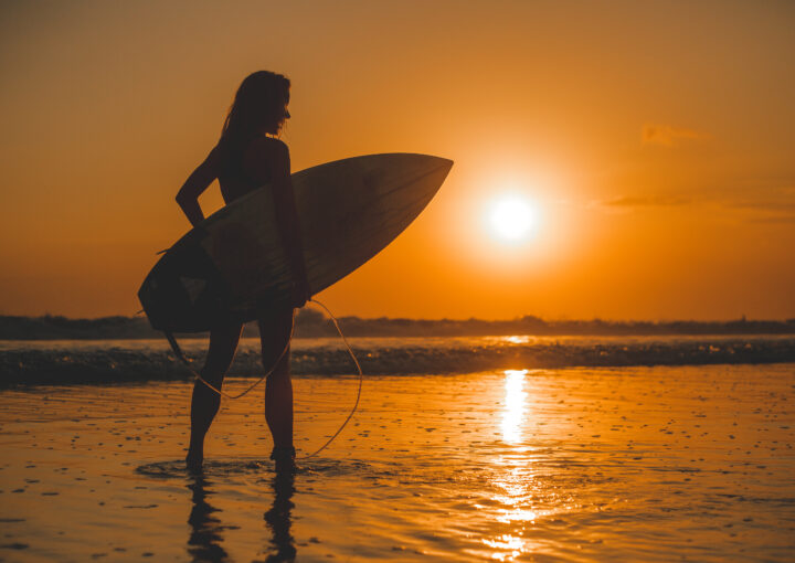 fille posant avec une planche au coucher du soleil
